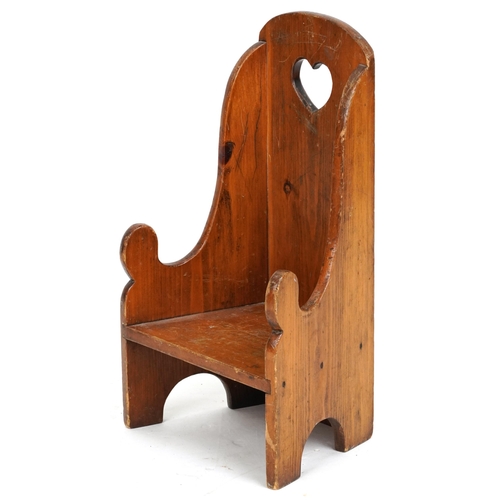 2132 - An early 20th century pine child's chair, the back pierced with a heart, raised on bracket feet, 61c... 