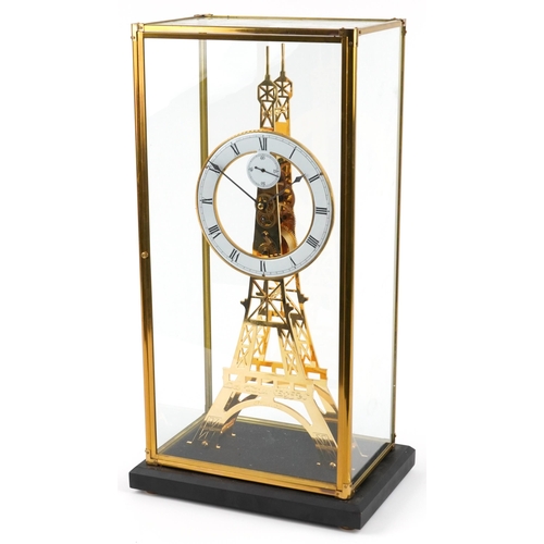 489 - A modern brass skeleton clock in the form of the Eiffel Tower, housed in a glass display case, havin... 