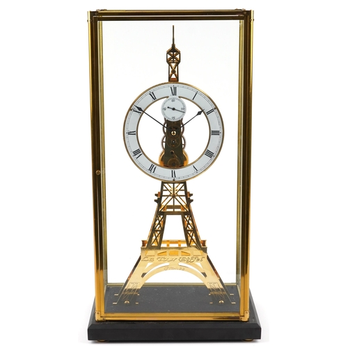 489 - A modern brass skeleton clock in the form of the Eiffel Tower, housed in a glass display case, havin... 