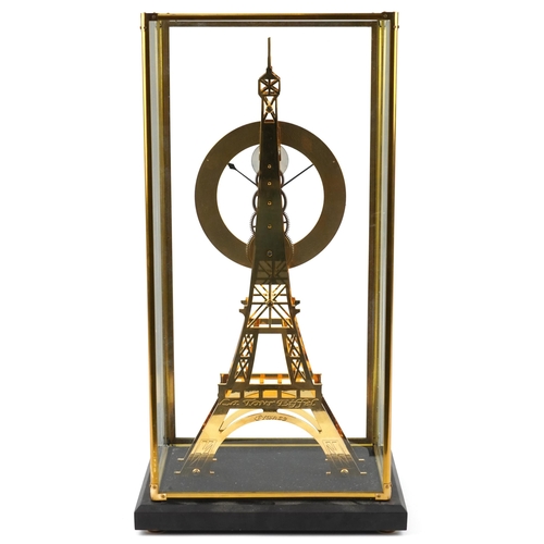 489 - A modern brass skeleton clock in the form of the Eiffel Tower, housed in a glass display case, havin... 