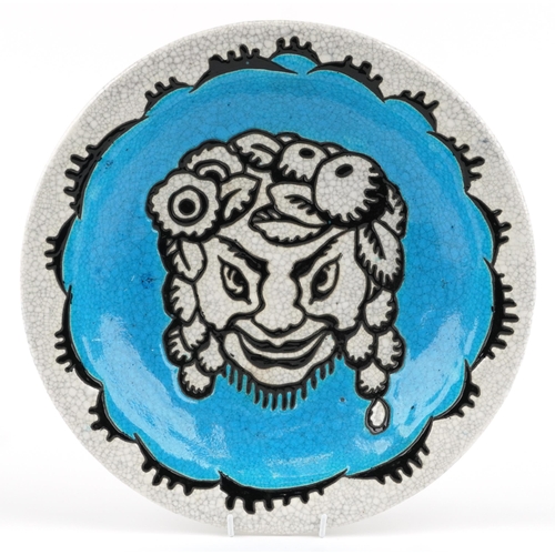 Charles Catteau for Keramis, an Art Deco enamelled pottery charger hand painted with a smiling Bacchus, impressed and inscribed marks to the reverse, 37cm in diameter.