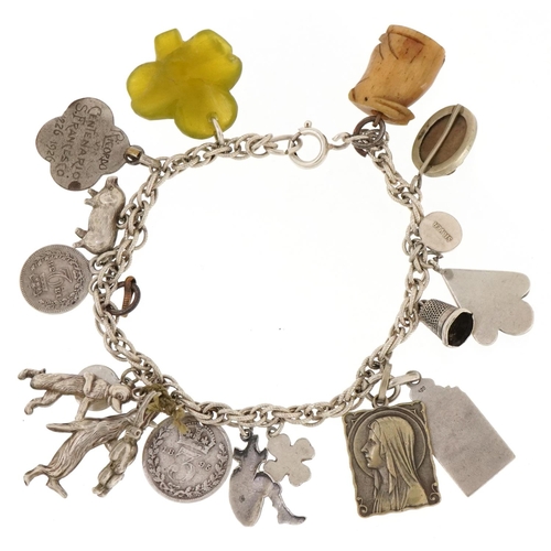 3131 - A silver charm bracelet with a collection of silver and white metal charms including Victorian coins... 