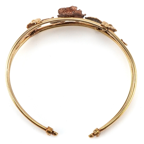 3001 - A 9ct two tone gold naturalistic rose design bangle, 9cm wide, 13.5g.