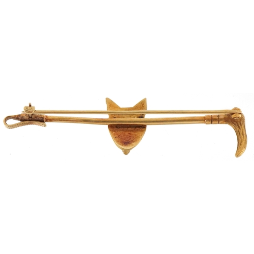 3020 - A hunting interest 14ct gold fox head and riding crop bar brooch with garnet eyes, 6.5cm wide, 6.5g.