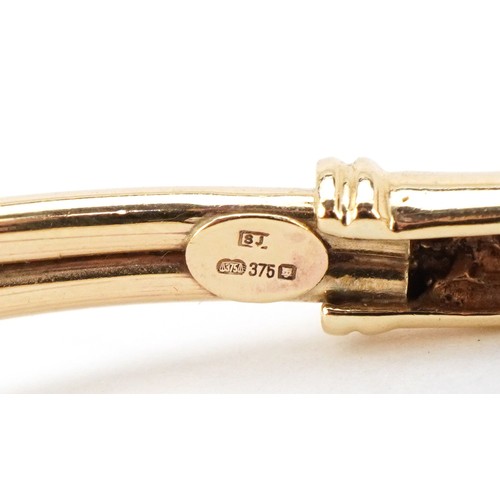 3055 - A 9ct gold and pink spinel bracelet in the form of a serpent, 6cm in diameter, 7.4g.