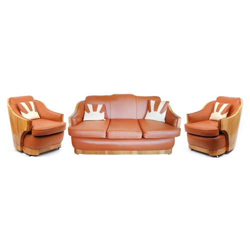 An Art Deco walnut three piece suite  comprising a settee and two armchairs, all upholstered in light brown leather, raised on casters, 84cm high, the settee width 170cm x 107cm D.