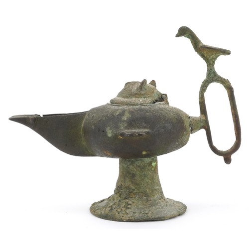 45 - An patinated metal oil lamp with a thumb rest in the form of a bird, 11cm high.