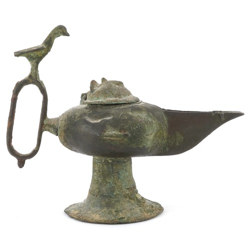 45 - An patinated metal oil lamp with a thumb rest in the form of a bird, 11cm high.
