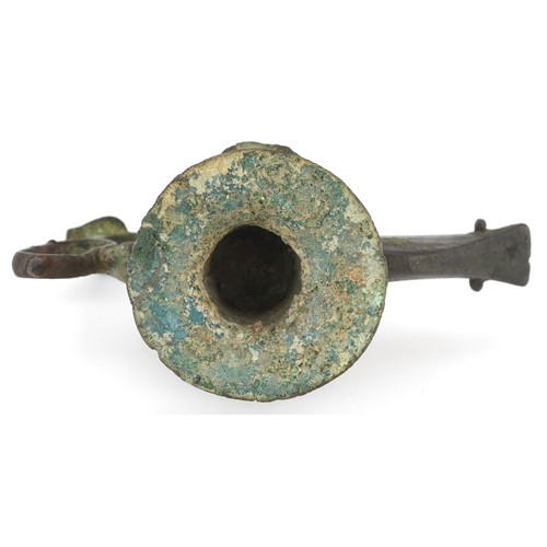 45 - An patinated metal oil lamp with a thumb rest in the form of a bird, 11cm high.
