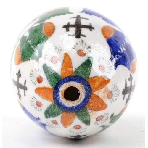 54 - A Turkish Armenian pottery hanging ball hand painted with mythical faces and motifs, 10cm high.