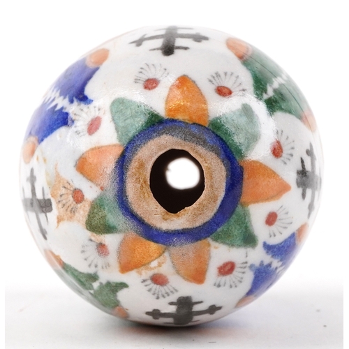 54 - A Turkish Armenian pottery hanging ball hand painted with mythical faces and motifs, 10cm high.