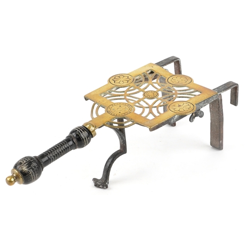 9 - A Victorian Arts and Crafts brass and cast iron trivet with wooden handle, 37cm wide.