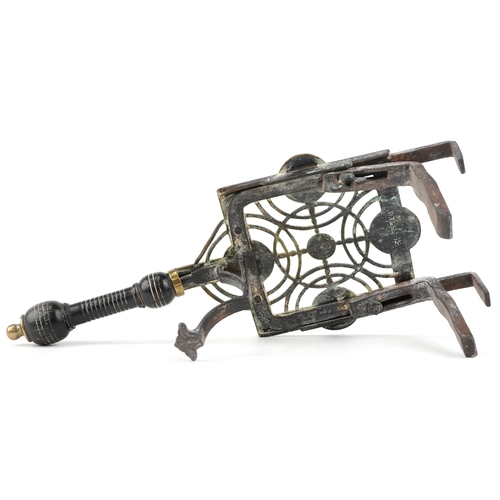9 - A Victorian Arts and Crafts brass and cast iron trivet with wooden handle, 37cm wide.