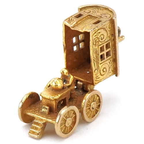A 9ct gold articulated charm in the form of a Gypsy waggon opening to reveal a fortune teller, 1.5cm in length, 3.7g.