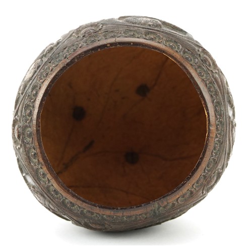 58 - A late 19th century Indian coconut tea caddy carved in relief with warriors and raised on three figu... 