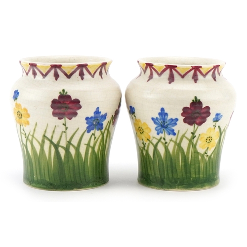 223 - E. Radford, a pair of Art Deco pottery vases, each with hand painted floral decoration, each bearing... 