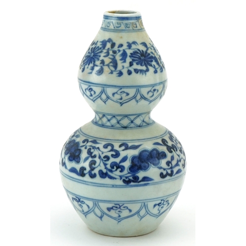 115 - A Chinese blue and white porcelain double gourd vase hand painted with scrolling foliage, 21cm high.
