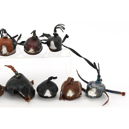 83 - Eleven vintage leather and fabric bird of prey falconry hoods, some with labels to the interior incl... 