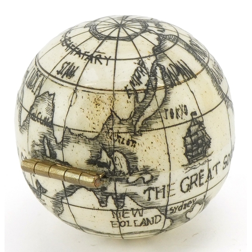 49 - A scrimshaw style etched bone compass in the form of a globe, 4cm in diameter.