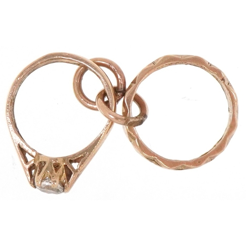 A 9ct gold charm in the form of two wedding rings set with a clear ...