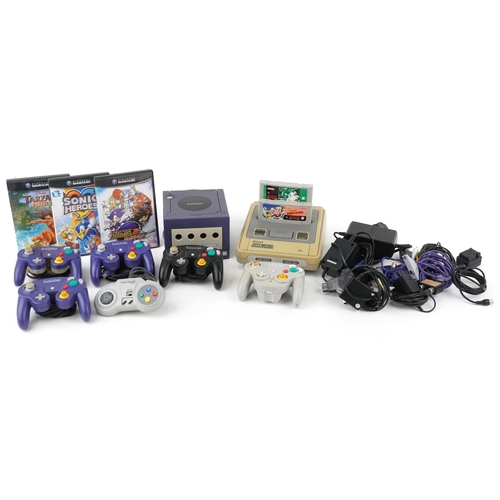 Two vintage games consoles with controllers and accessories comprising Super Nintendo Entertainment System and Nintendo Game Cube.