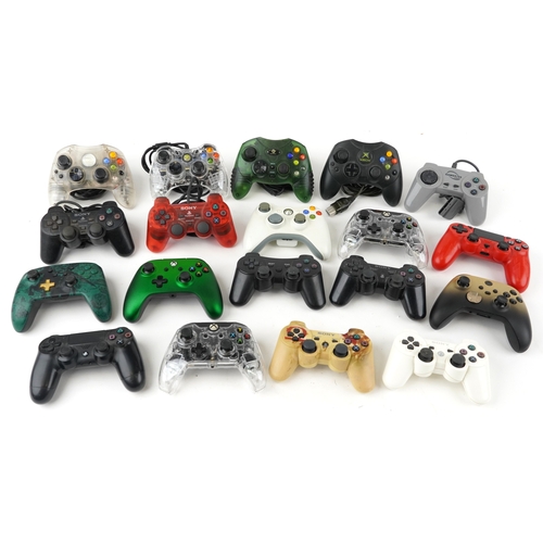 A collection of Xbox and PlayStation games console controllers.
