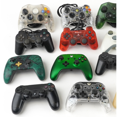 A collection of Xbox and PlayStation games console controllers.