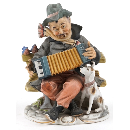 604 - A 20th century porcelain figure group of an accordion player with a dog and two perched birds, 19cm ... 
