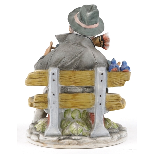 604 - A 20th century porcelain figure group of an accordion player with a dog and two perched birds, 19cm ... 