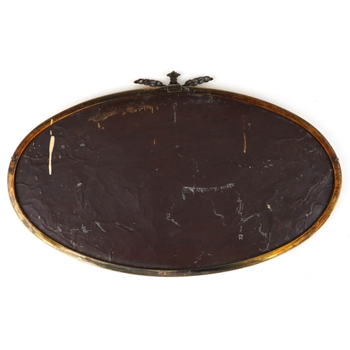 2021 - An early 20th century oval bevelled glass and brass mirror with stylized leaf design, 76cm wide.