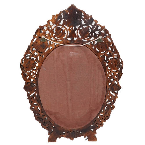  A mid 20th century Indian carved softwood oval mirror, the outer frame profusely carved and pierced ... 
