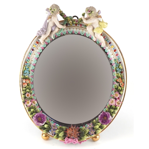 27 - A Sitzendorf German porcelain oval easel mirror with encrusted floral decoration and surmounted with... 