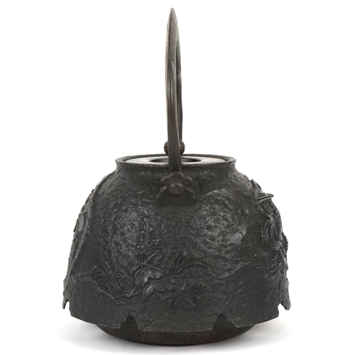  A Japanese cast iron teapot, 19th century, decorated with a phoenix bearing a nine character mark to... 