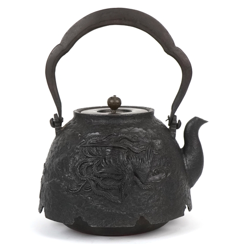  A Japanese cast iron teapot, 19th century, decorated with a phoenix bearing a nine character mark to... 