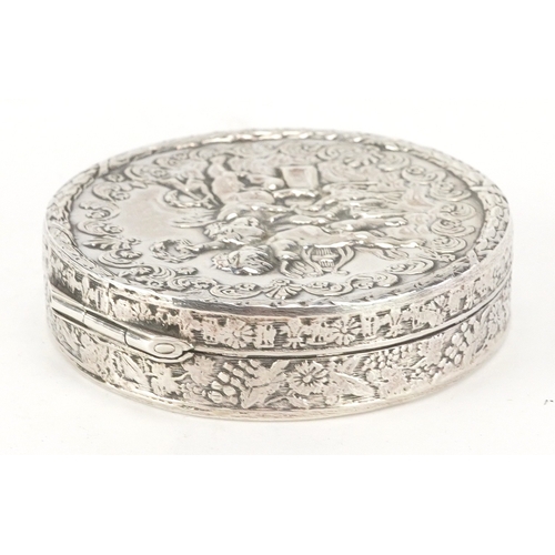 52 - A silver circular snuff box embossed with Putti, London import marks 1976, 5.3cm in diameter, 35.8g.