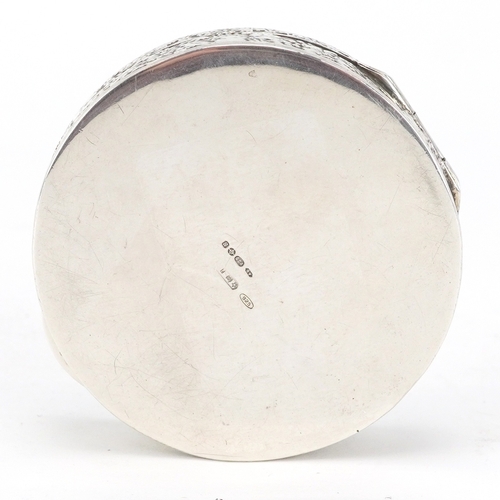 52 - A silver circular snuff box embossed with Putti, London import marks 1976, 5.3cm in diameter, 35.8g.
