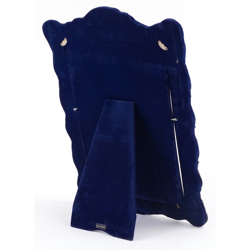 39 - Henry Matthews, a very large silver easel photo frame profusely embossed with flowers, foliage and a... 