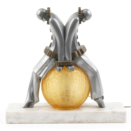  An Art Deco aluminium and glass Pierrot figural table lamp with amber frosted glass shade, raised on... 