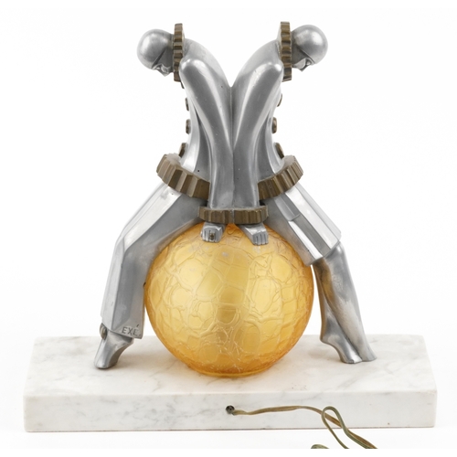  An Art Deco aluminium and glass Pierrot figural table lamp with amber frosted glass shade, raised on... 