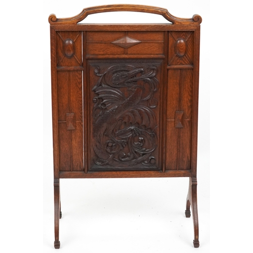  A late Victorian Arts & Crafts oak firescreen, the central panel carved with a dragon, raised on dow... 