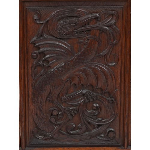 A late Victorian Arts & Crafts oak firescreen, the central panel carved with a dragon, raised on dow... 