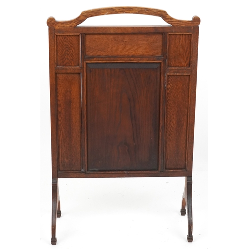  A late Victorian Arts & Crafts oak firescreen, the central panel carved with a dragon, raised on dow... 