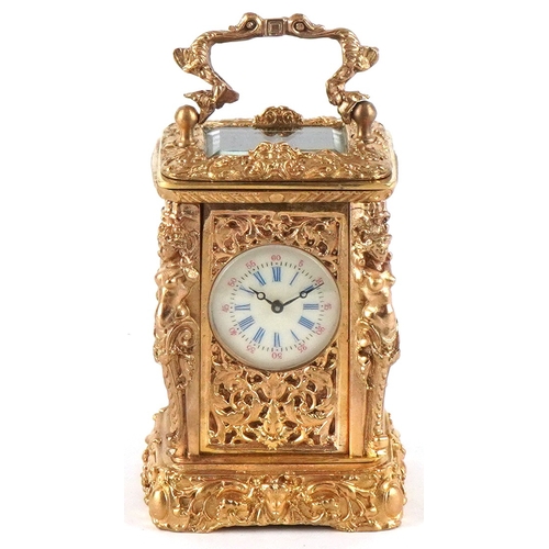 131 - A miniature gilt brass Rococo style carriage clock with swing handle, the dial having Roman numerals... 