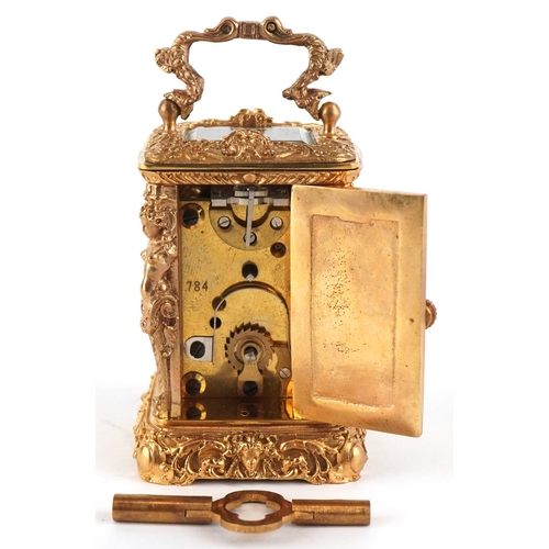 131 - A miniature gilt brass Rococo style carriage clock with swing handle, the dial having Roman numerals... 