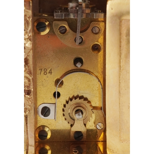 131 - A miniature gilt brass Rococo style carriage clock with swing handle, the dial having Roman numerals... 