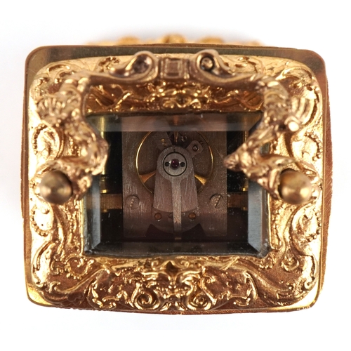 131 - A miniature gilt brass Rococo style carriage clock with swing handle, the dial having Roman numerals... 