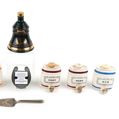 673 - Seven Wade porcelain decanters and a silver plated cake slice, the largest 19cm high.