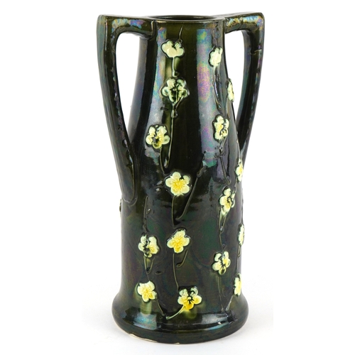 332 - An Art Nouveau twin handled vase having a lustre glaze, decorated in relief with flowers, 24cm high.