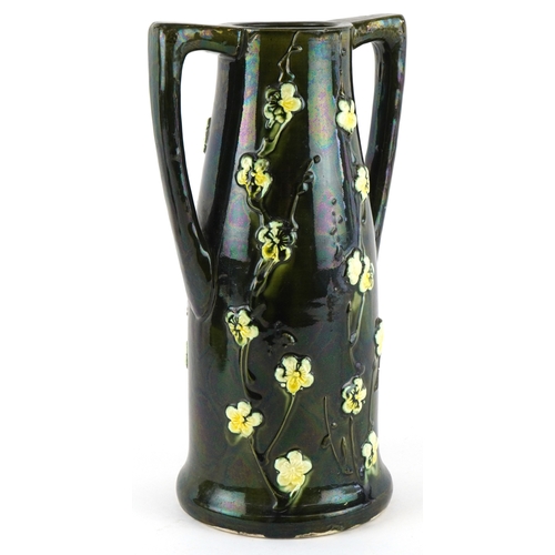 332 - An Art Nouveau twin handled vase having a lustre glaze, decorated in relief with flowers, 24cm high.