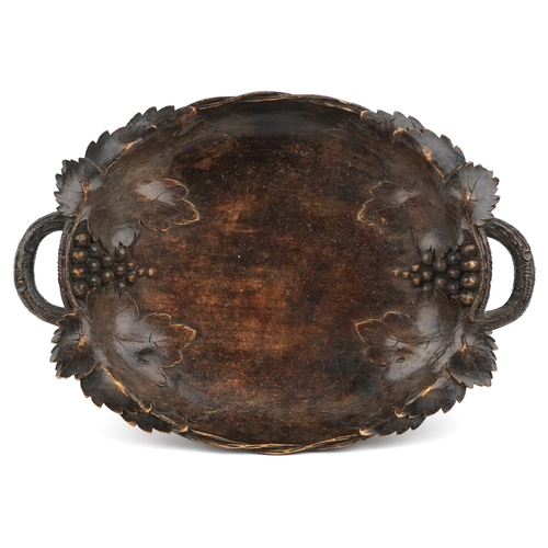 1884 - An early 20th century beech oval centrepiece bowl carved with leaves, with pierced handles, 9cm high... 